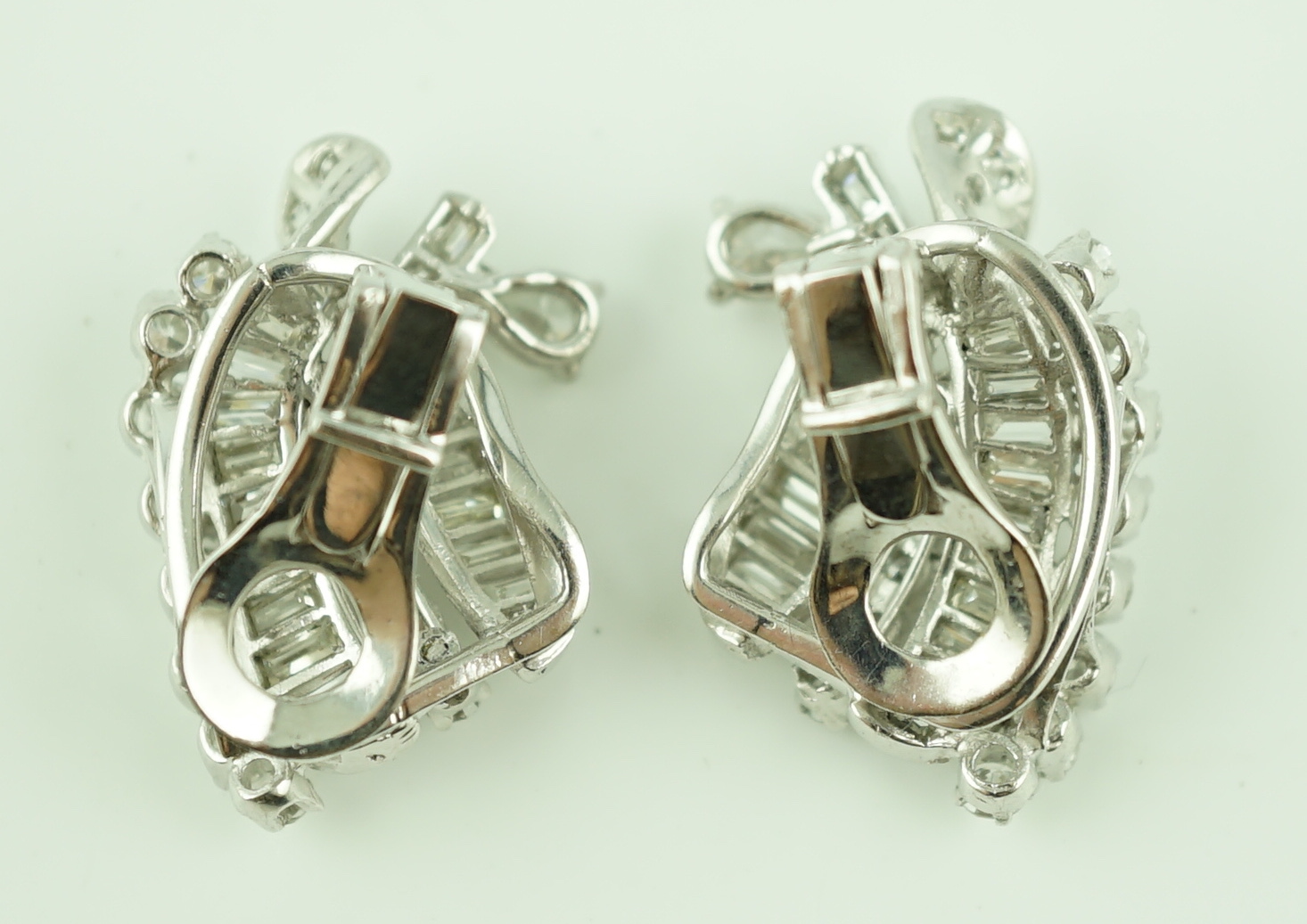 A pair of platinum and round cut, baguette cut and pear cut diamond cluster set scrolling ear clips